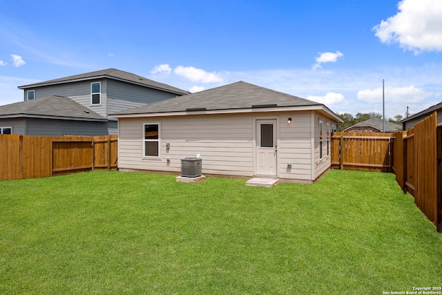 rear view of property with central AC unit and a yard