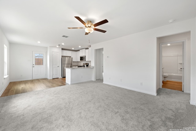 unfurnished living room with light colored carpet and ceiling fan