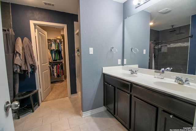 bathroom featuring tile patterned floors, vanity, and a tile shower