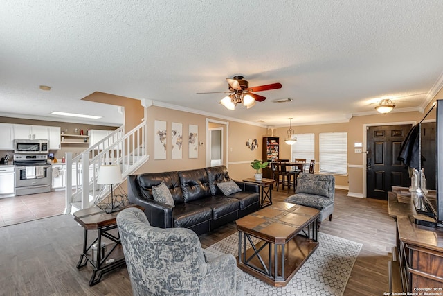 living room featuring hardwood / wood-style flooring, ceiling fan, crown molding, and a textured ceiling