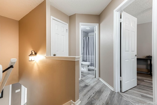 corridor with light hardwood / wood-style flooring and a textured ceiling