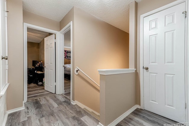 corridor with hardwood / wood-style flooring and a textured ceiling