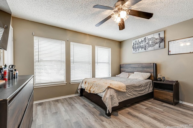 bedroom featuring multiple windows, ceiling fan, light hardwood / wood-style floors, and a textured ceiling