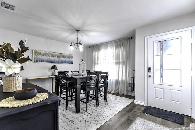 dining area with hardwood / wood-style floors, a textured ceiling, and a notable chandelier