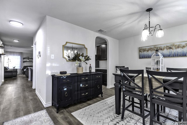 dining room with dark wood-type flooring and a chandelier