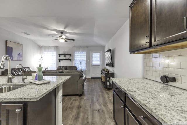 kitchen with dark brown cabinets, dark hardwood / wood-style floors, light stone countertops, and sink