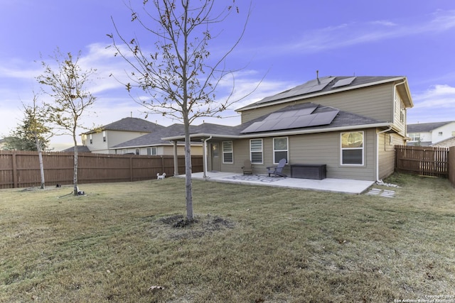 rear view of property with a lawn, a patio area, and solar panels