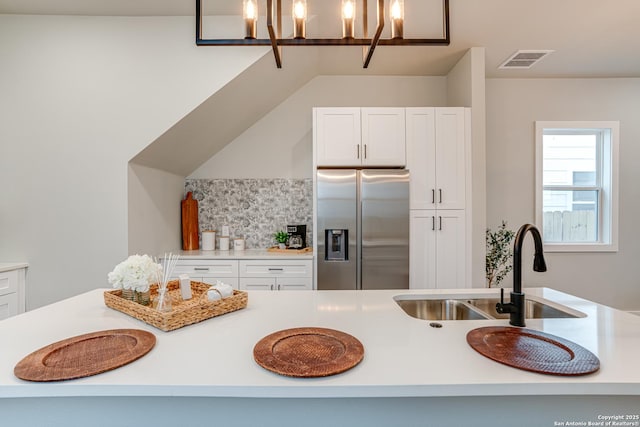 kitchen with stainless steel refrigerator with ice dispenser, sink, decorative light fixtures, white cabinets, and a chandelier