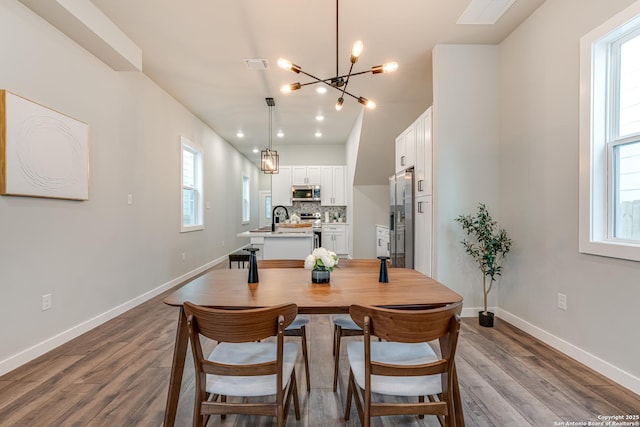 dining room featuring a chandelier, a healthy amount of sunlight, and light hardwood / wood-style floors