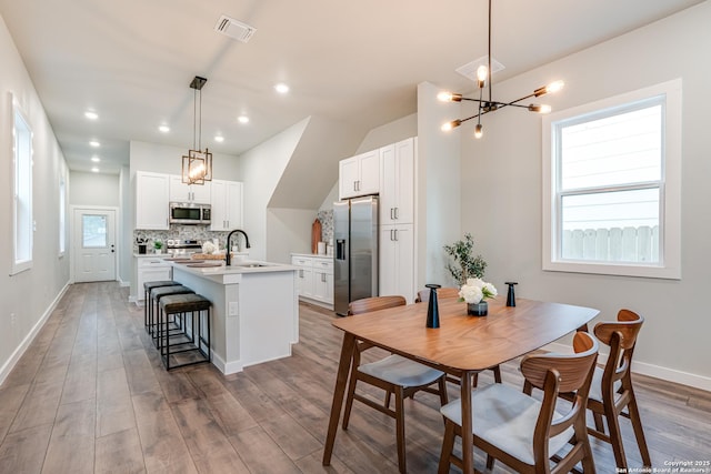 dining room featuring sink, wood-type flooring, and a notable chandelier