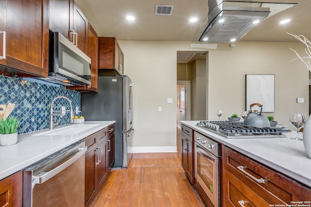 kitchen with sink, stainless steel appliances, light hardwood / wood-style flooring, backsplash, and island exhaust hood