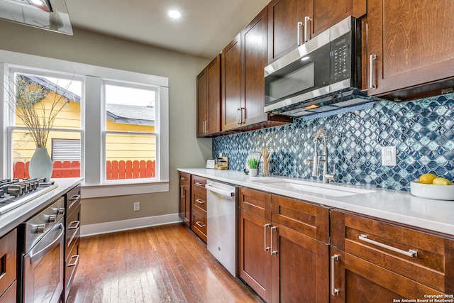 kitchen featuring stainless steel appliances, light hardwood / wood-style flooring, tasteful backsplash, and sink