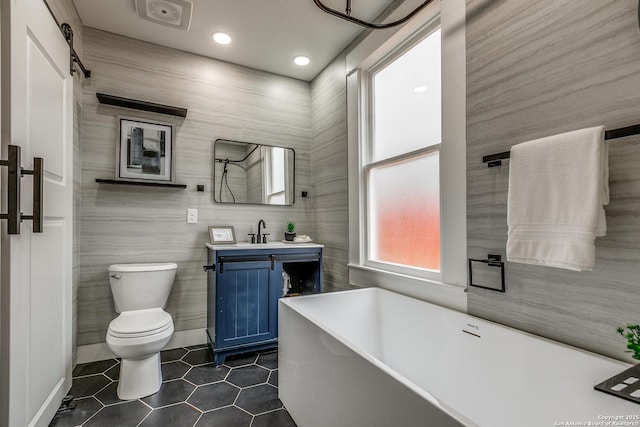 bathroom with vanity, toilet, a bathtub, and tile walls