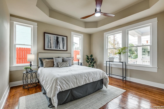 bedroom featuring hardwood / wood-style floors, a raised ceiling, and ceiling fan