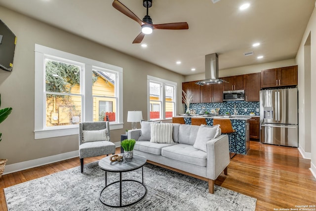 living room with ceiling fan, plenty of natural light, and light hardwood / wood-style flooring