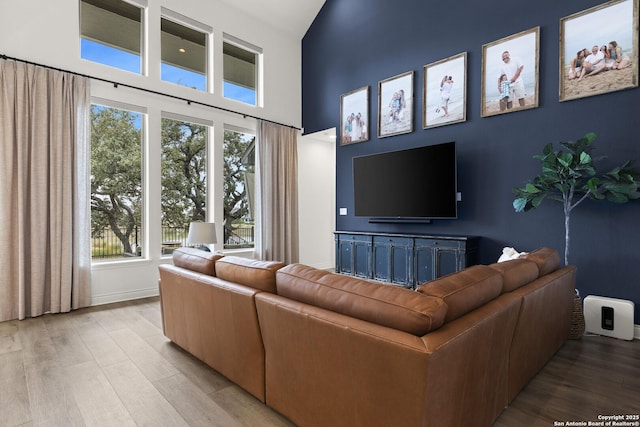 living room with plenty of natural light, a towering ceiling, and light hardwood / wood-style floors