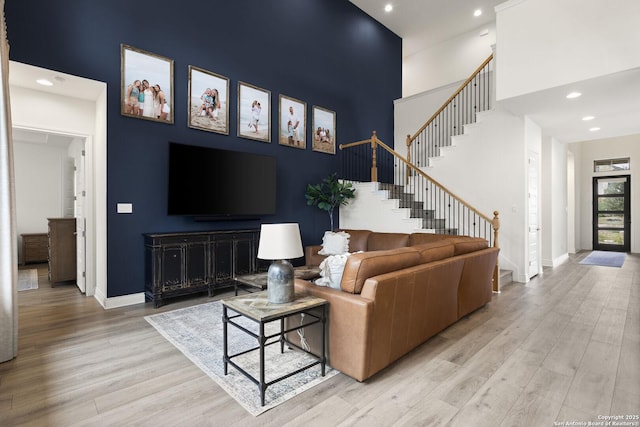 living room featuring light wood-type flooring and a high ceiling