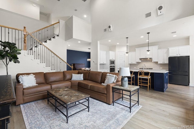 living room featuring a high ceiling, light hardwood / wood-style floors, and sink