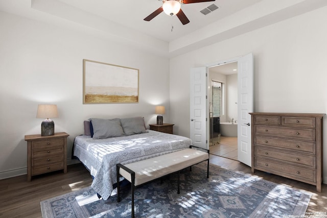 bedroom featuring ensuite bathroom, ceiling fan, a raised ceiling, and dark wood-type flooring