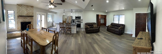 dining room featuring a fireplace, dark hardwood / wood-style flooring, vaulted ceiling, and ceiling fan