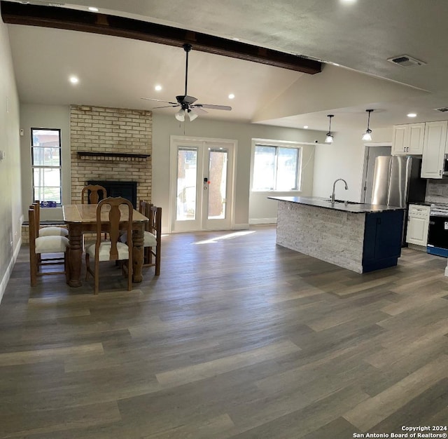 kitchen with white cabinets, dark hardwood / wood-style flooring, a center island with sink, and a healthy amount of sunlight