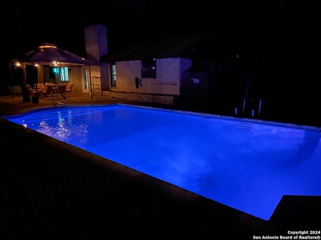 pool at twilight featuring a patio