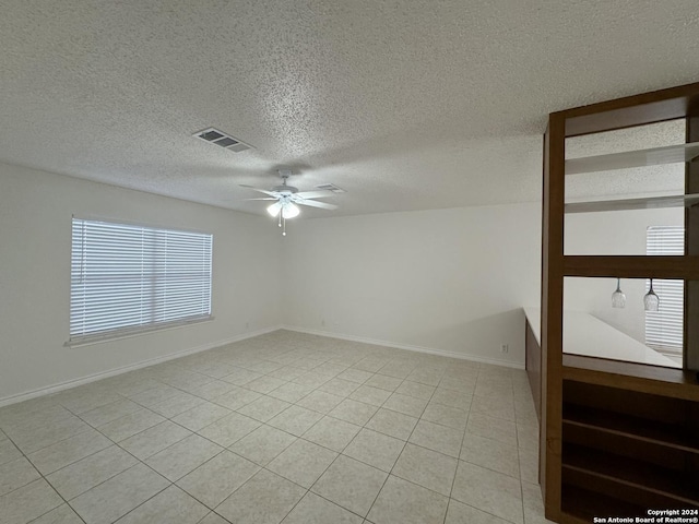 empty room with light tile patterned floors, a textured ceiling, and ceiling fan