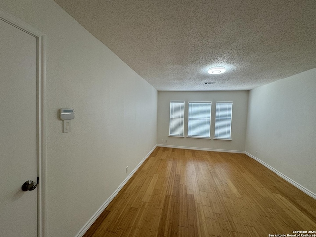 empty room featuring light wood-type flooring and a textured ceiling