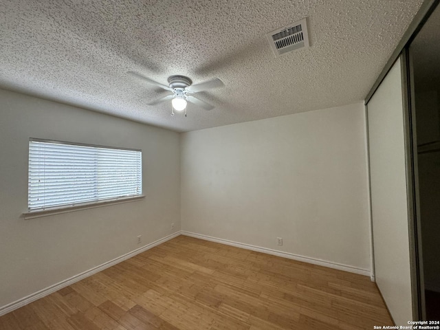 spare room featuring a textured ceiling, light hardwood / wood-style flooring, and ceiling fan