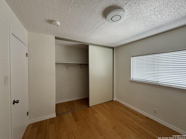 unfurnished bedroom featuring wood-type flooring, a textured ceiling, and a closet