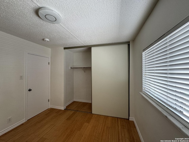 unfurnished bedroom featuring a textured ceiling, light hardwood / wood-style flooring, and a closet