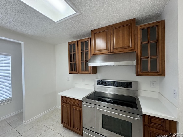 kitchen with stainless steel range with electric stovetop, light tile patterned floors, and a textured ceiling