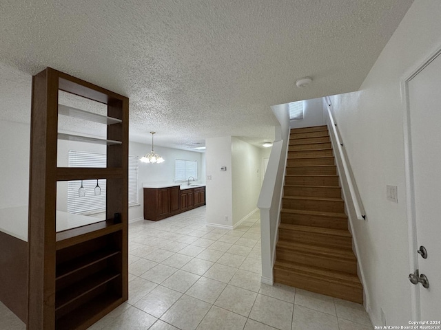 stairs featuring tile patterned floors, a notable chandelier, and sink