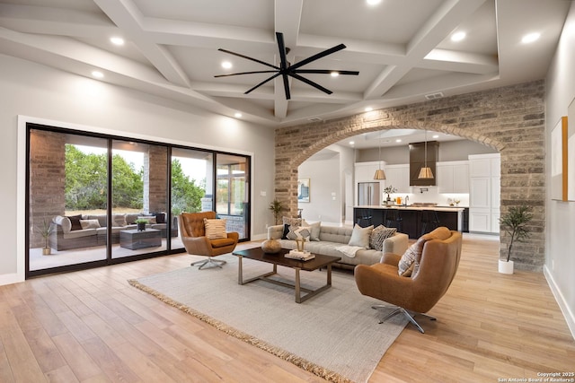 living room with ceiling fan, beam ceiling, light wood-type flooring, and coffered ceiling