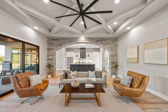 living room featuring ceiling fan, beam ceiling, light wood-type flooring, and coffered ceiling