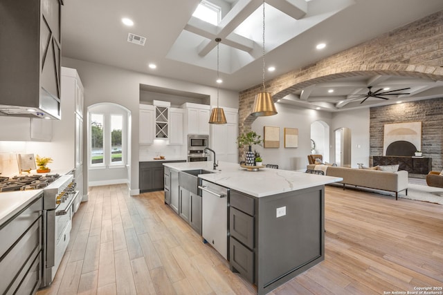 kitchen featuring stainless steel appliances, ceiling fan, white cabinetry, hanging light fixtures, and a large island