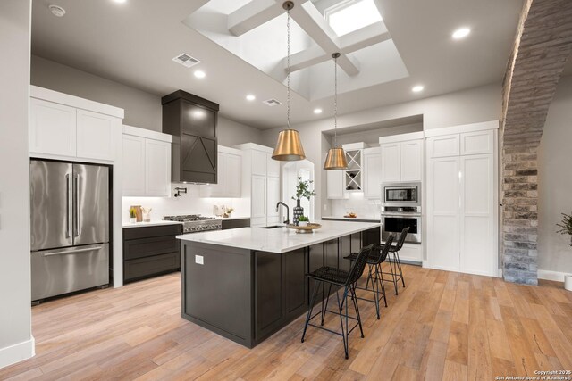 kitchen featuring light hardwood / wood-style floors, sink, stainless steel appliances, and a kitchen island with sink