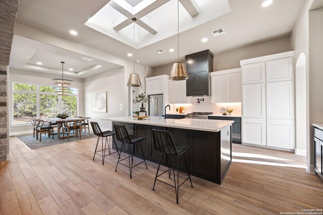 kitchen featuring white cabinets, pendant lighting, a tray ceiling, and a spacious island