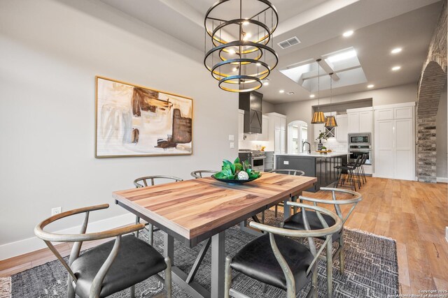 dining room with sink, light hardwood / wood-style flooring, and an inviting chandelier