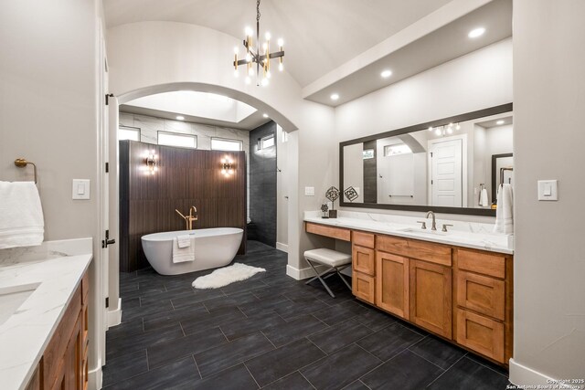 bathroom featuring a tub to relax in, vanity, vaulted ceiling, and an inviting chandelier