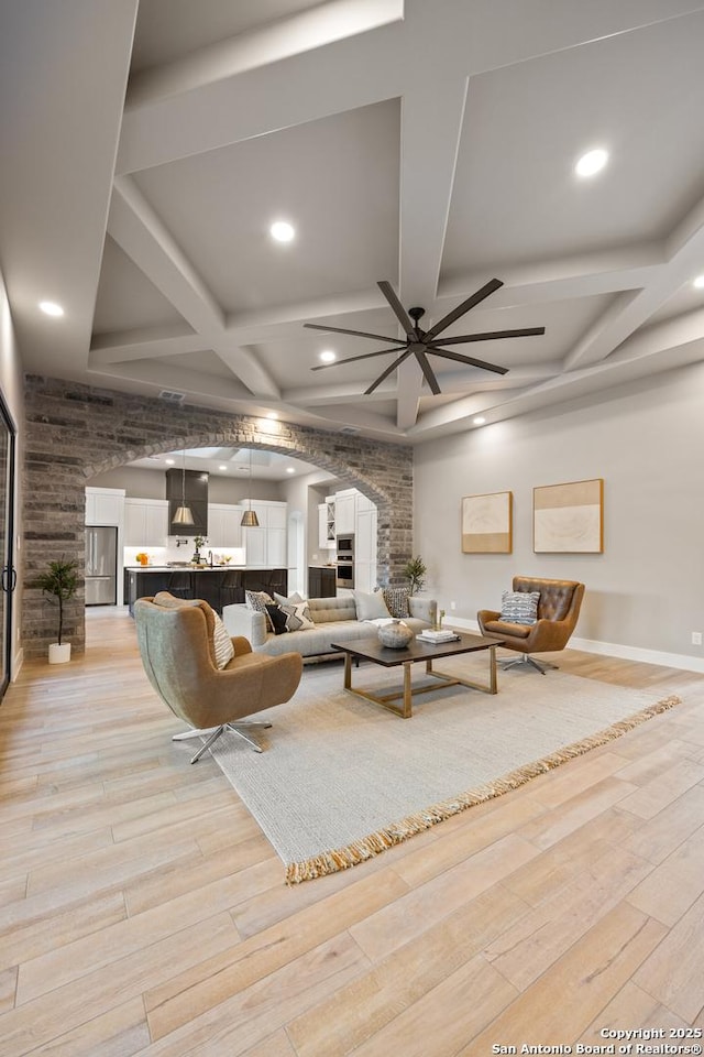 living room featuring beamed ceiling, ceiling fan, light hardwood / wood-style floors, and coffered ceiling