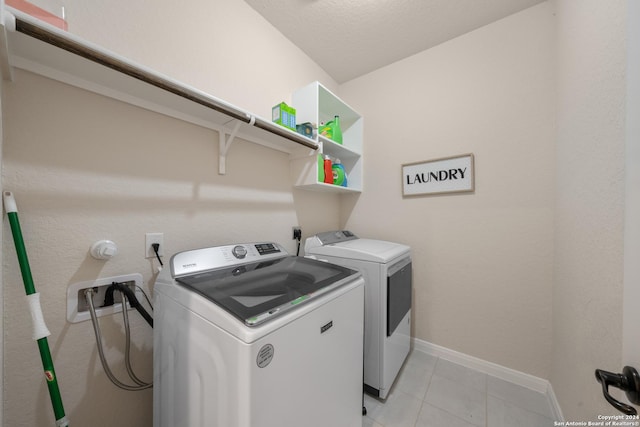 laundry area with independent washer and dryer and light tile patterned floors