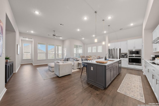 kitchen with appliances with stainless steel finishes, gray cabinetry, a breakfast bar, a center island with sink, and white cabinets