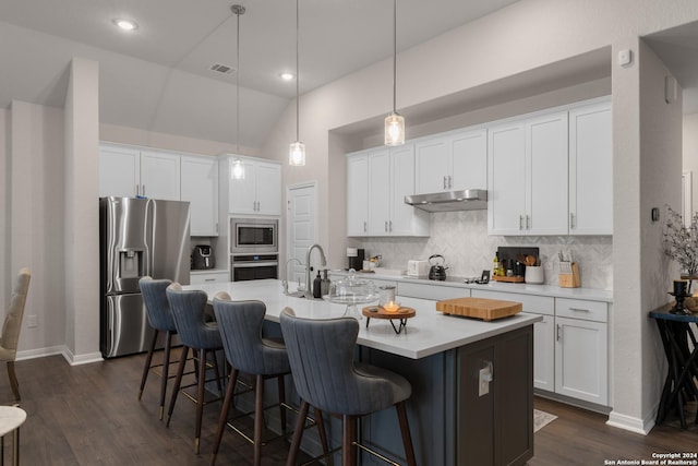 kitchen with white cabinets, stainless steel appliances, hanging light fixtures, and an island with sink