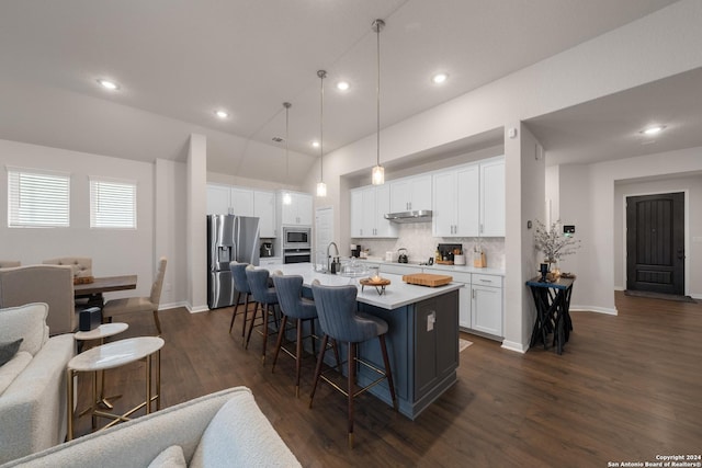 kitchen with stainless steel appliances, a kitchen breakfast bar, pendant lighting, a kitchen island with sink, and white cabinets