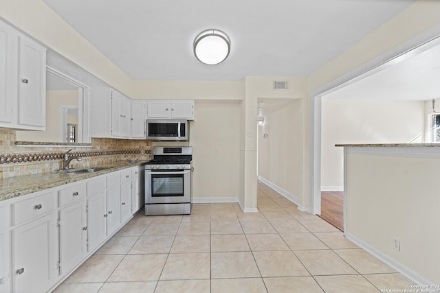 kitchen featuring sink, tasteful backsplash, light stone counters, white cabinets, and appliances with stainless steel finishes