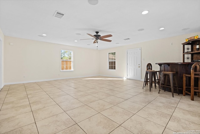 interior space with bar, ceiling fan, and light tile patterned flooring