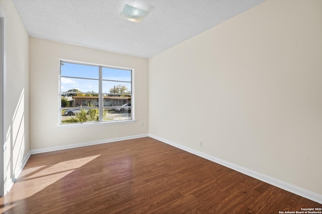 spare room featuring wood-type flooring and a textured ceiling