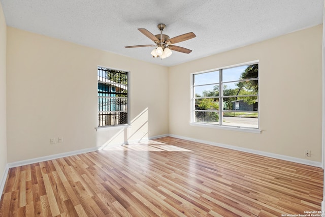 empty room with plenty of natural light, a textured ceiling, and light hardwood / wood-style flooring