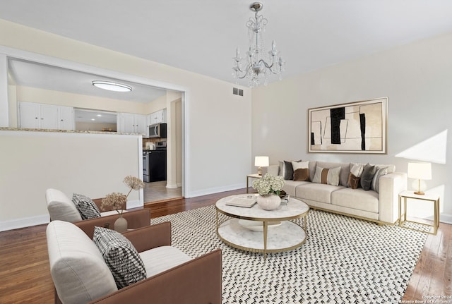 living room with a notable chandelier and dark wood-type flooring